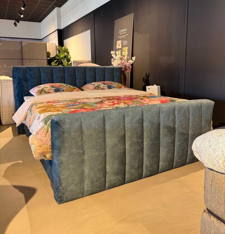 Boxspring Bulge Norma Timeless showroommodel in slaapkameropstelling met grijze gestoffeerde hoofdbord en matras.