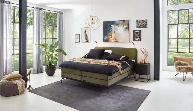 Elektrische Caresse Boxspring 3000 met gestoffeerd hoofdbord en verstelbare matrassen in een moderne slaapkamer.