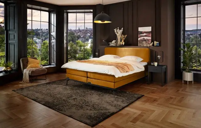 Boxspring Caresse 3050 met gestoffeerd hoofdbord en matras, tweepersoons, getoond in een moderne slaapkameromgeving.