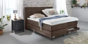 Boxspring Caresse 7000 tweepersoons elektrisch verstelbaar met grijze bekleding en hoofdbord in slaapkameromgeving