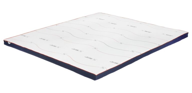 M line Cool Motion Topper Firm op een bed met witte lakens en een blauwe ventilerende hoes voor fris slaapklimaat.