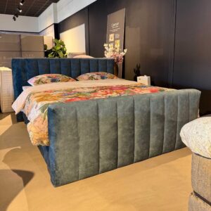 Boxspring Bulge Norma Timeless showroommodel in slaapkameropstelling met grijze gestoffeerde hoofdbord en matras.